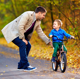Отец учит ребенка кататься на велосипеде